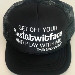 May include: Black trucker hat with a white mesh back. The front of the hat has white text that reads "Get off your Instawtwitface and play with me Talk Story Cali".