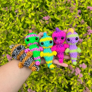 Puede incluir: Cinco pulseras de gomas el&aacute;sticas de colores con forma de personajes de dibujos animados. Las pulseras son verdes, amarillas, rosas, moradas y blancas y negras.