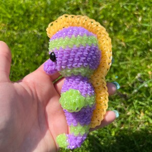 Puede incluir: Un caballito de mar de gomas el&aacute;sticas moradas y verdes con una crin de gomas el&aacute;sticas amarillas.
