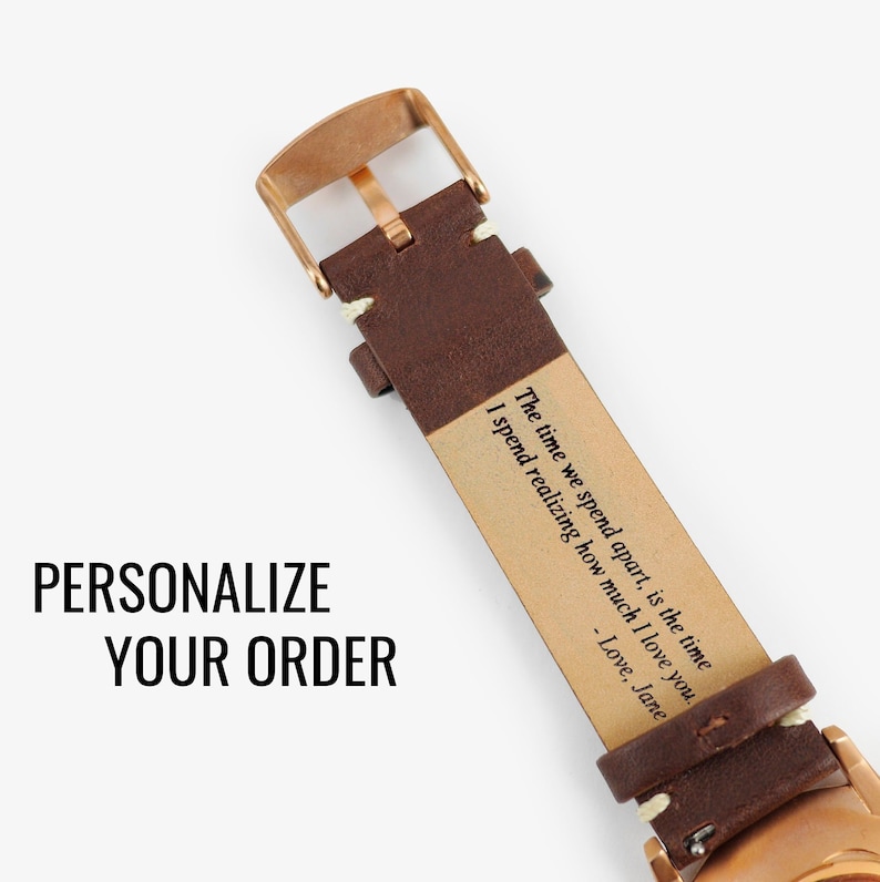 May include: Close-up of a brown leather watch strap with a gold buckle. The strap has white stitching and a personalized message: "The time we spend apart, is the time I spend realizing how much I love you."