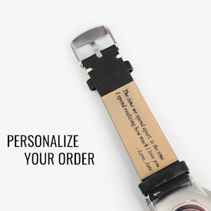 May include: A black leather watch band with a silver buckle. The band has a personalized message that reads: "The time we spend apart, is the time I spend realizing how much I love you. - Love, Jane"