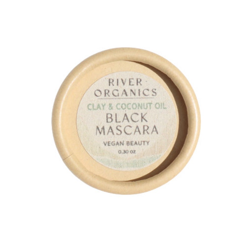 Puede incluir: Un peque&ntilde;o recipiente redondo de cart&oacute;n con una etiqueta que dice "River Organics Arcilla & Aceite de Coco Mascara Negra Vegan Beauty 0.30 oz."