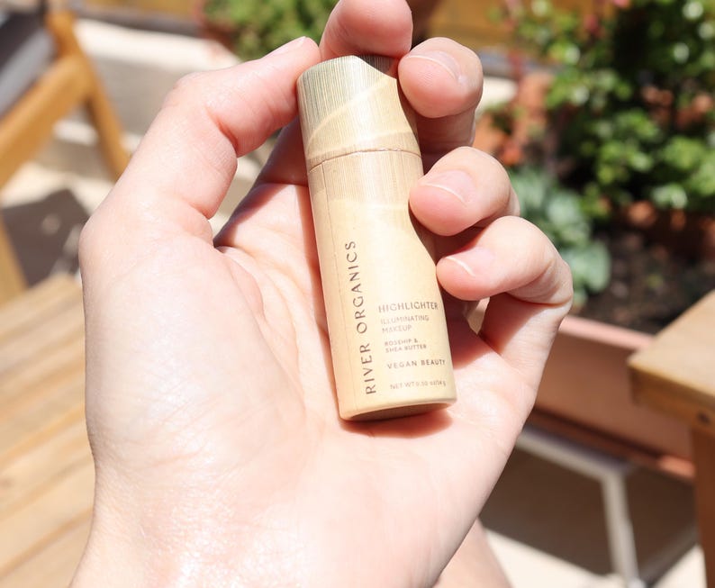 Zero-waste vegan highlighter stick in eco-friendly paper tube packaging, clean beauty makeup alternative to plastic containers.