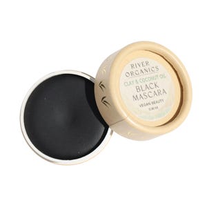 Puede incluir: Un peque&ntilde;o recipiente redondo beige con una tapa negra. El recipiente est&aacute; etiquetado como "River Organics Clay & Coconut Oil Black Mascara Vegan Beauty 0.30 oz".