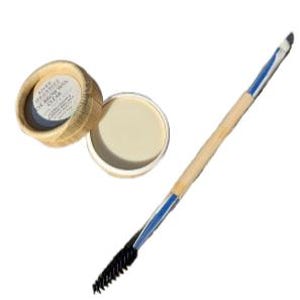 May include: A clear eyebrow wax in a small, round, bamboo container with the lid off, next to a double-ended brow brush. The brush has a wooden handle with blue accents and a spoolie on one end and angled brush on the other.