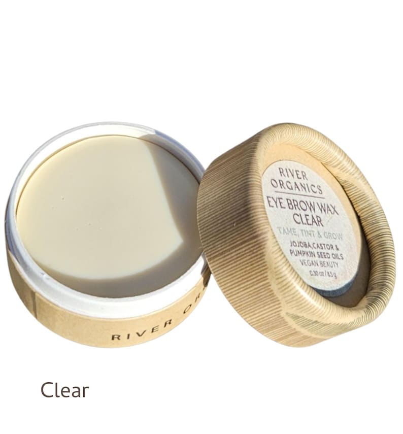 May include: A clear eye brow wax in a round, open container. The product is labeled "River Organics Eye Brow Wax Clear" with text indicating it tames, tints, and grows brows. The container is made of cardboard and contains 0.30 oz of product.