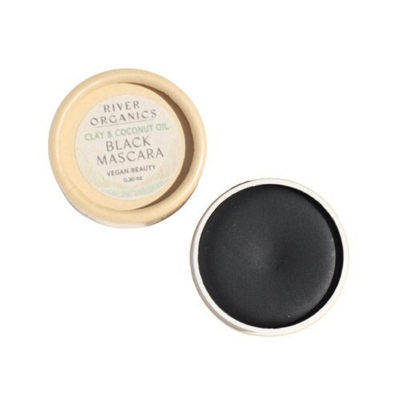 Puede incluir: Un peque&ntilde;o recipiente redondo de m&aacute;scara de pesta&ntilde;as negra con una etiqueta que dice "River Organics Arcilla & Aceite de Coco M&aacute;scara Negra Belleza Vegana 0.24 oz".