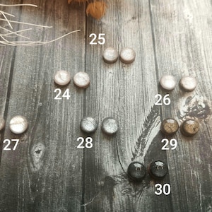 Puede incluir: Surtido de 10 pequeñas decoraciones redondas en varios colores y acabados, incluyendo plata, oro y blanco. Las decoraciones están numeradas del 24 al 30.