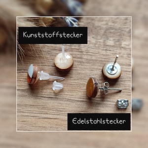 May include: A pair of wooden earrings with different colored designs. The earrings are shown with both plastic and stainless steel posts.