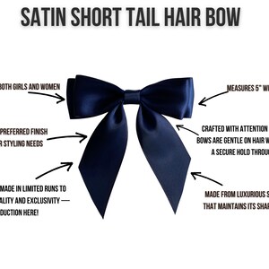 May include: A navy blue satin hair bow with short tails. The bow measures 5 inches wide and 8 inches long. It is made from luxurious satin ribbon that maintains its shape over time. The bow is crafted with attention to detail and is gentle on hair while offering a secure hold throughout the day.