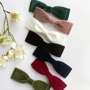 May include: Assortment of velvet bow ties in various colors, including green, pink, white, black, navy blue, burgundy, and olive green.