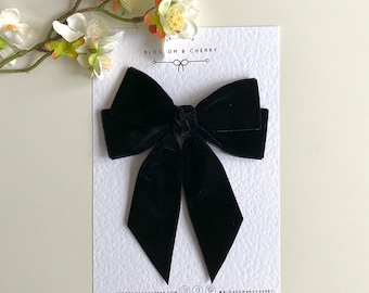 May include: A large black velvet bow with two long tails. The bow is on a white card with the text "BLOSSOM & CHERRY" and the website address "www.blossomandcherry.com".