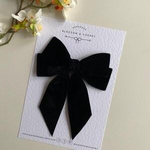 Pode incluir: Um grande la&ccedil;o de veludo preto com uma ponta pontiaguda. O la&ccedil;o &eacute; feito &agrave; m&atilde;o por Blossom & Cherry.