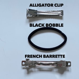 May include: Three hair accessories: a silver alligator clip, a black hair tie, and a silver French barrette.