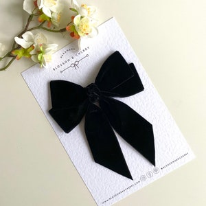 Pode incluir: La&ccedil;o de veludo preto feito &agrave; m&atilde;o com um n&oacute; simples no centro. O la&ccedil;o &eacute; exibido em um cart&atilde;o branco com o texto "Handmade Blossom & Cherry" e o endere&ccedil;o do site "www.blossomandcherry.com".