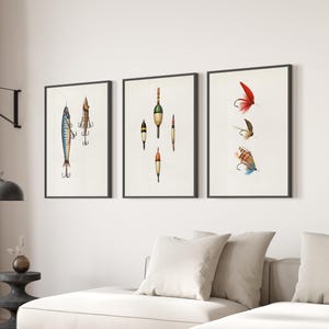 Puede incluir: Tres impresiones artísticas enmarcadas con ilustraciones de aparejos de pesca vintage. Las impresiones presentan dibujos detallados de señuelos y flotadores de pesca, sobre un fondo blanco. Los marcos son negros y la obra de arte se exhibe en un salón.
