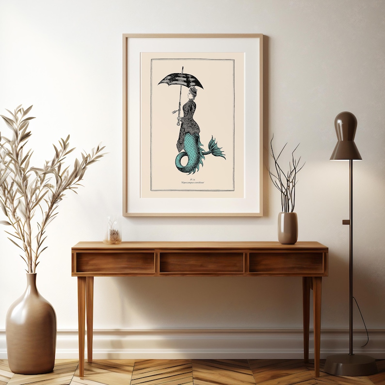 May include: A vintage illustration of a mermaid with a black and white umbrella. The mermaid is wearing a black dress and has a teal tail. The illustration is framed and hanging on a wall above a wooden console table.