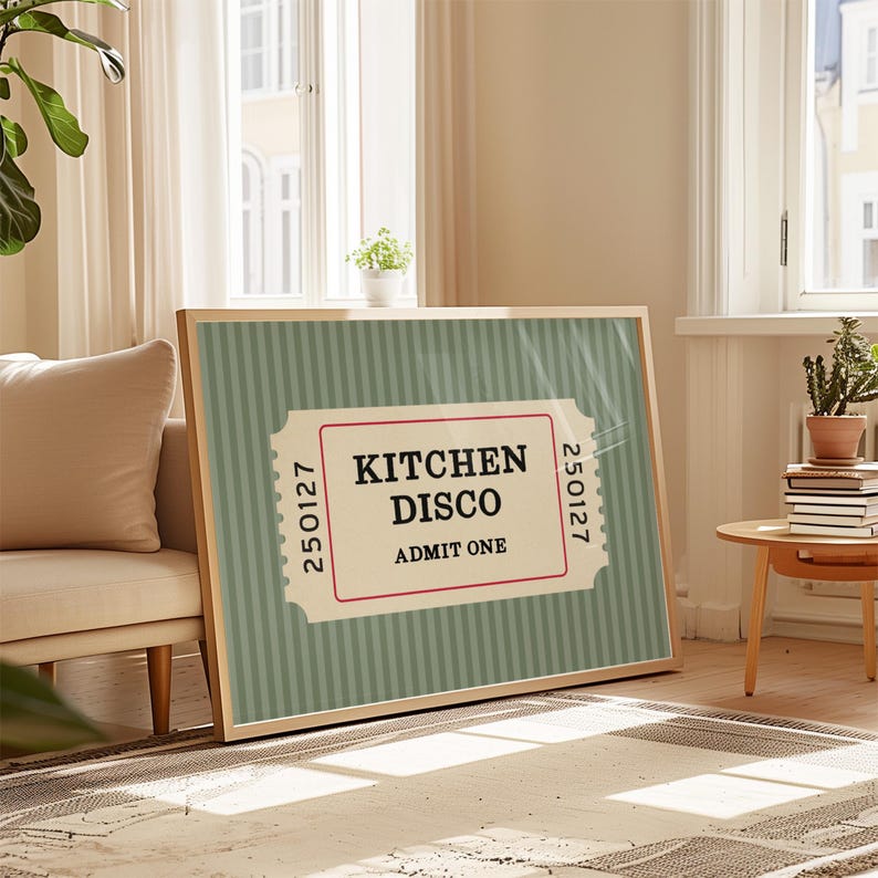 Puede incluir: Un estampado enmarcado con un dise&ntilde;o de boleto, que muestra las palabras "KITCHEN DISCO" en negro sobre un fondo crema, enmarcado por un borde rojo. El fondo tiene un patr&oacute;n de rayas verde claro. El estampado est&aacute; sobre una alfombra.
