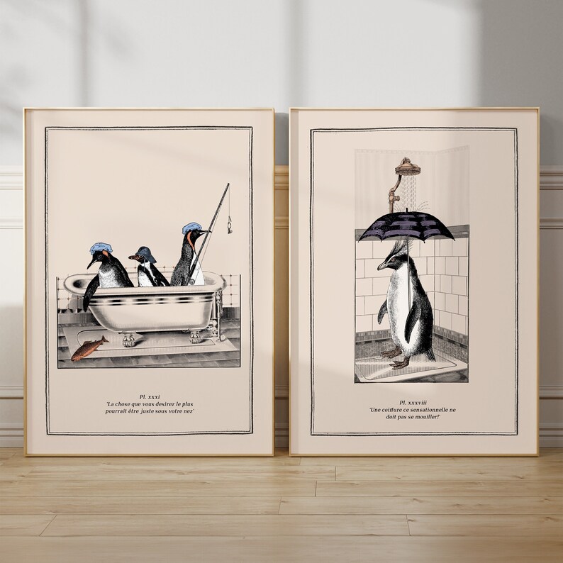 Op de afbeelding: Twee ingelijste kunstprints met illustraties van pingu&iuml;ns. E&eacute;n toont pingu&iuml;ns in een bad, de andere een pingu&iuml;n onder een paraplu in een douche. Franse tekst is inbegrepen. Gouden frames.