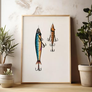 May include: A framed print featuring two detailed illustrations of fishing lures. One lure is blue, yellow, and purple, while the other is orange and brown. Both lures have multiple hooks and are set against a cream background.