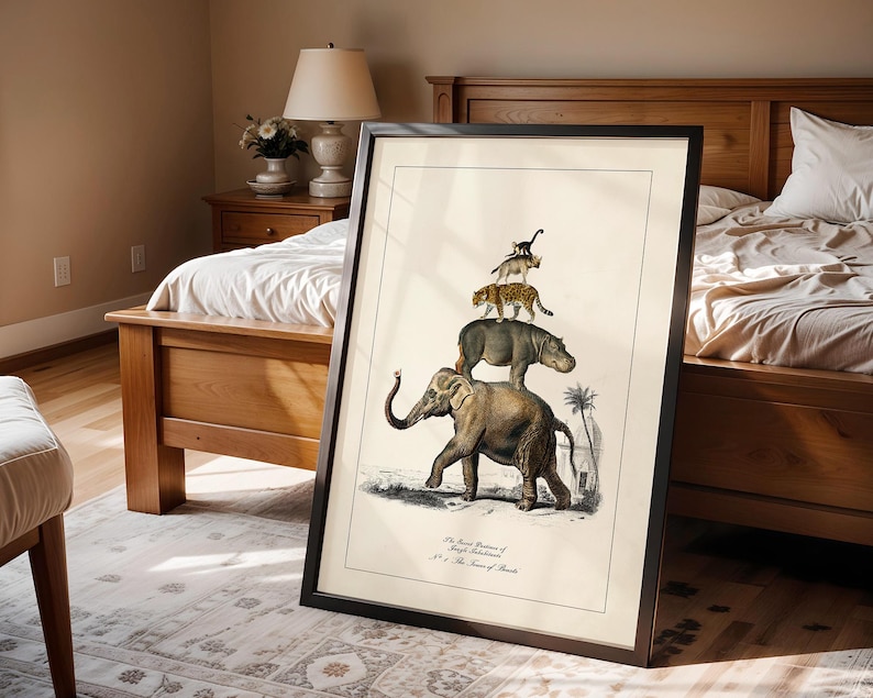 May include: Framed vintage-style print featuring an elephant, hippo, leopard, and monkey stacked on top of each other. The artwork is in a black frame and leans against a bed. The print includes text at the bottom. The room has a neutral color palette.
