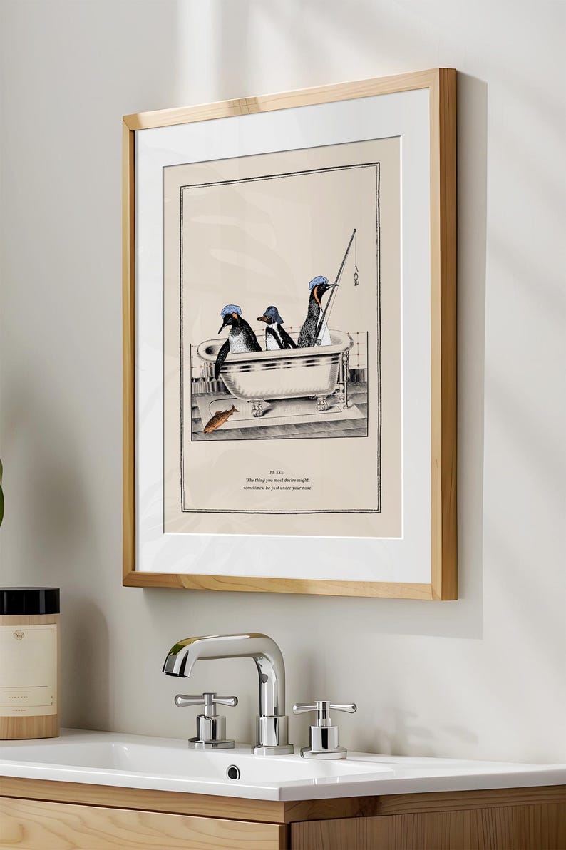 Op de afbeelding: Ingelijste kunstdruk met drie pingu&iuml;ns in een badkuip, waarvan &eacute;&eacute;n aan het vissen is. De pingu&iuml;ns dragen blauwe hoeden. Het kunstwerk is in zwart-wit met een beige achtergrond en een houten lijst. De print bevat tekst.