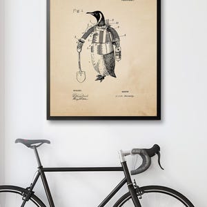 May include: Framed patent print featuring a penguin with robotic arms, holding a shovel and lantern. The text reads "Patent Office" and "Robotic Arms for Penguin Explorer." The artwork is in black and white, with a vintage aesthetic.