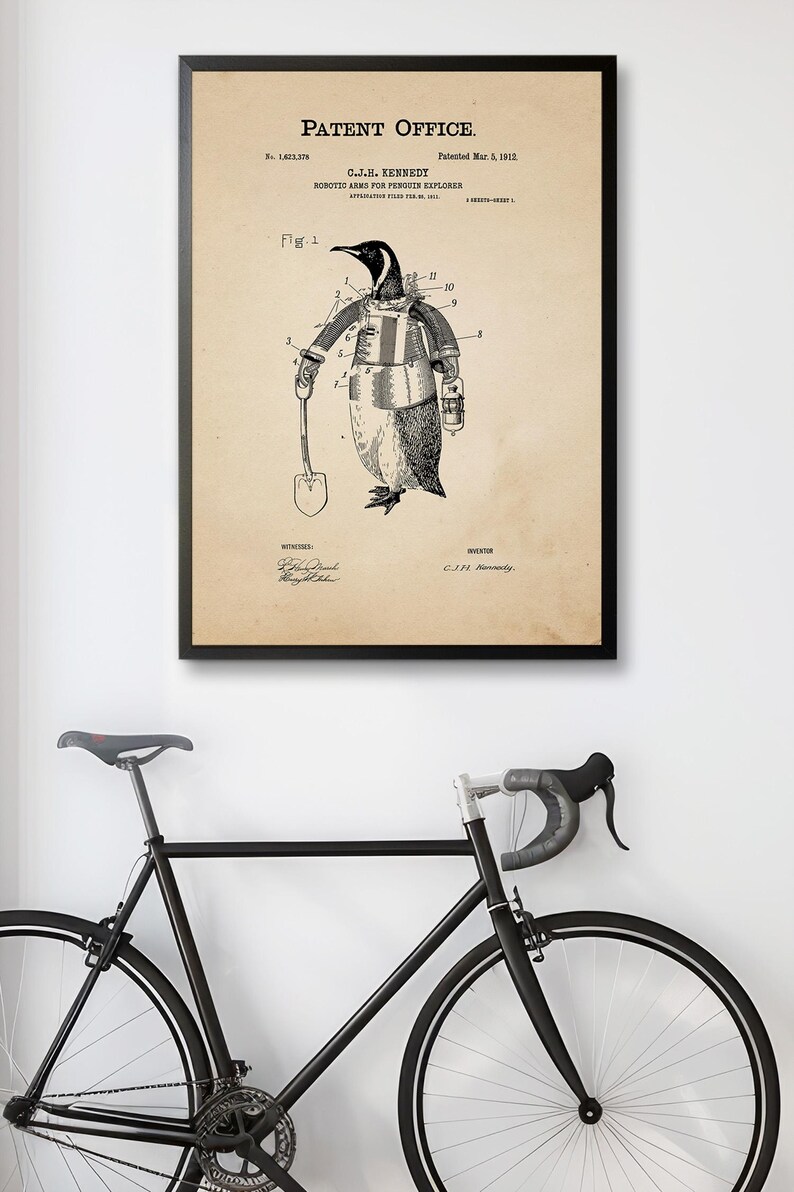 May include: Framed patent print featuring a penguin with robotic arms, holding a shovel and lantern. The text reads "Patent Office" and "Robotic Arms for Penguin Explorer." The artwork is in black and white, with a vintage aesthetic.