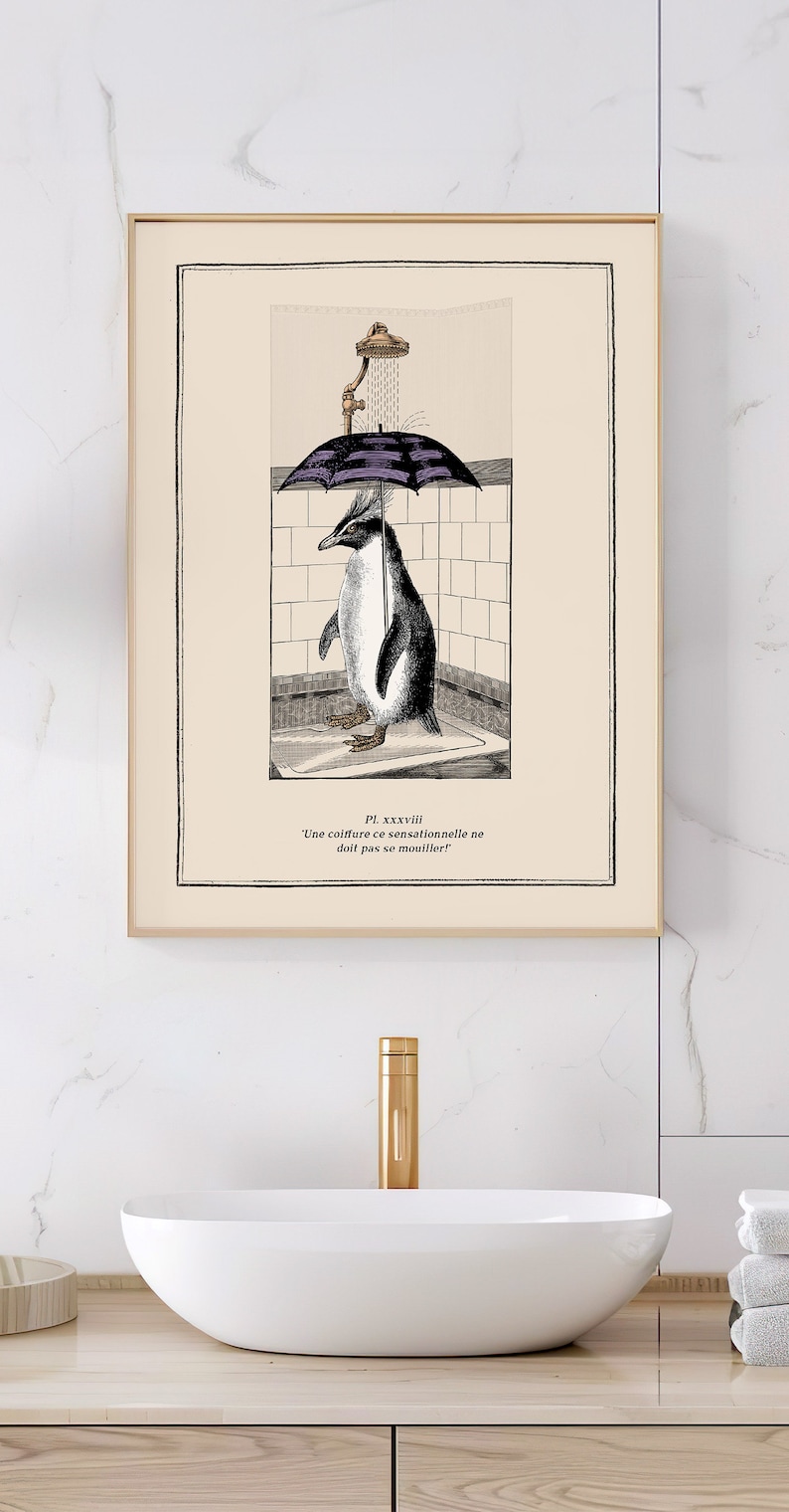 Op de afbeelding: Ingelijste kunstafdruk met een pingu&iuml;n onder een paraplu in een douche. De zwart-wit illustratie heeft een vintage esthetiek, met Franse tekst. Het kunstwerk staat boven een witte wastafel met een gouden kraan.