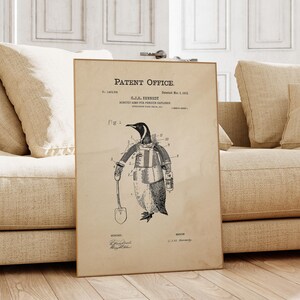 May include: A framed vintage patent print featuring a penguin in a suit holding a shovel. The print is labeled "Patent Office" and includes technical drawings and text. The artwork is displayed on a light-colored background.