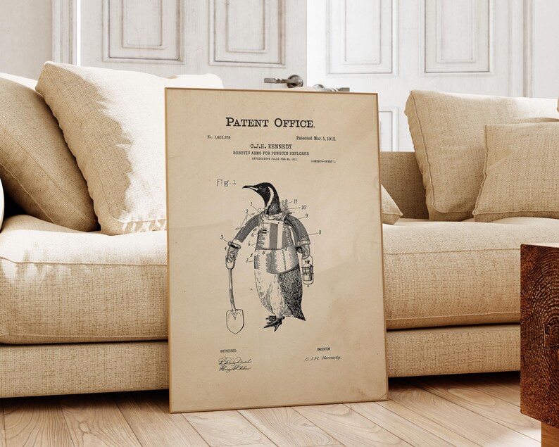 May include: A framed vintage patent print featuring a penguin in a suit holding a shovel. The print is labeled "Patent Office" and includes technical drawings and text. The artwork is displayed on a light-colored background.