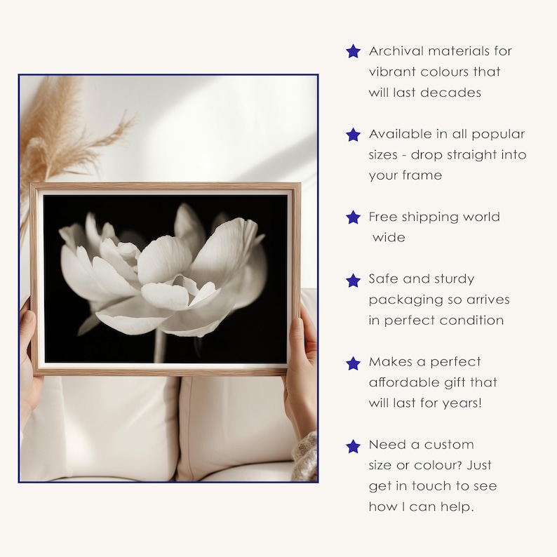 May include: A black and white floral print in a wooden frame. The image features a close-up of a flower with soft, textured petals. The frame is held by hands against a neutral background. The text on the right side says "Archival materials for vibrant colours that will last decades."