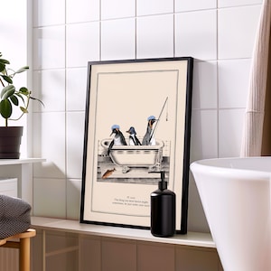 Op de afbeelding: Een ingelijste kunstdruk met drie pingu&iuml;ns in een badkuip, &eacute;&eacute;n met een hengel. Het kunstwerk is in zwart-wit met een beige achtergrond. De print bevat de tekst: "Het ding dat je het meest begeert, kan soms net onder je neus zijn."