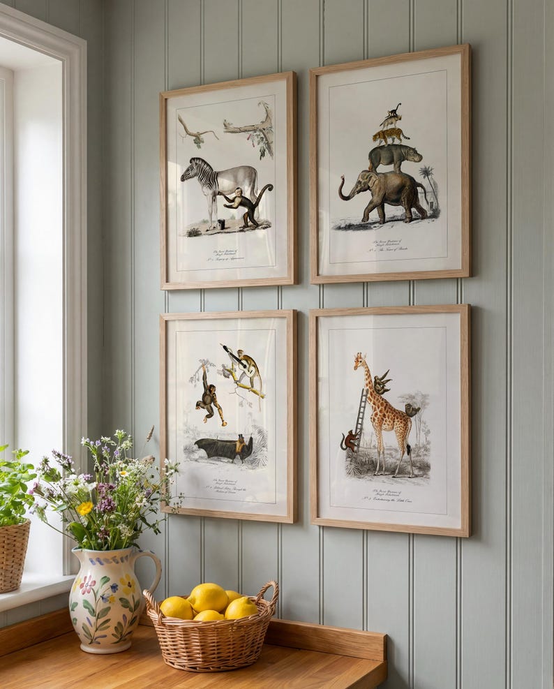May include: Four framed animal prints hang on a light blue wall. The prints feature detailed illustrations of a zebra with a monkey, an elephant with stacked animals, monkeys, and a giraffe with a ladder. The frames are light wood.