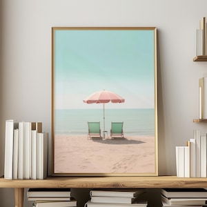May include: A pink and white striped beach umbrella with two green chairs on a sandy beach with a blue ocean in the background.