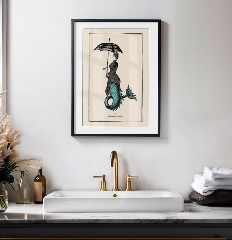 May include: A black framed print of a mermaid with a black and white umbrella. The mermaid is wearing a black dress and has a teal tail. The print is on a cream background and has the text "Pl. 18.  Hippocampus coronatus" at the bottom.
