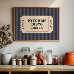 Puede incluir: Una impresi&oacute;n enmarcada con el texto "KITCHEN DISCO ADMIT ONE" en un dise&ntilde;o de boleto. El fondo es azul marino con rayas verticales. La impresi&oacute;n est&aacute; encima de una encimera con varios frascos, cuencos y una tetera naranja.