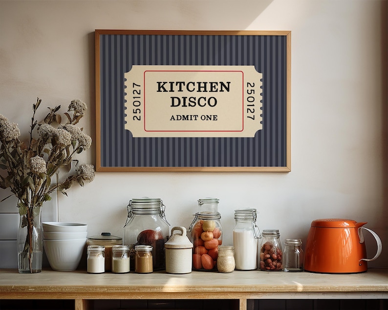Puede incluir: Una impresi&oacute;n enmarcada con el texto "KITCHEN DISCO ADMIT ONE" en un dise&ntilde;o de boleto. El fondo es azul marino con rayas verticales. La impresi&oacute;n est&aacute; encima de una encimera con varios frascos, cuencos y una tetera naranja.