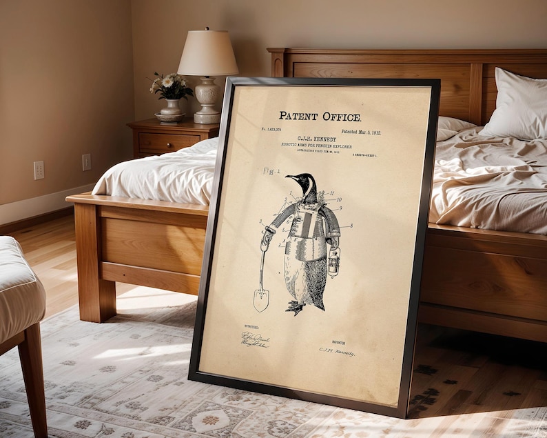 May include: Framed patent print featuring a penguin in an explorer's suit, holding a shovel. The print is in black and white, with the text "Patent Office" at the top. The frame is black, and the print is displayed in a bedroom setting.