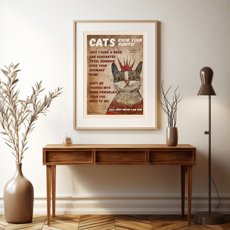 May include: A vintage-style poster with a cartoon cat wearing a crown. The poster reads "Cats Know Your Rights!" and includes text about cat dominance over humans. The poster has a distressed, aged look.