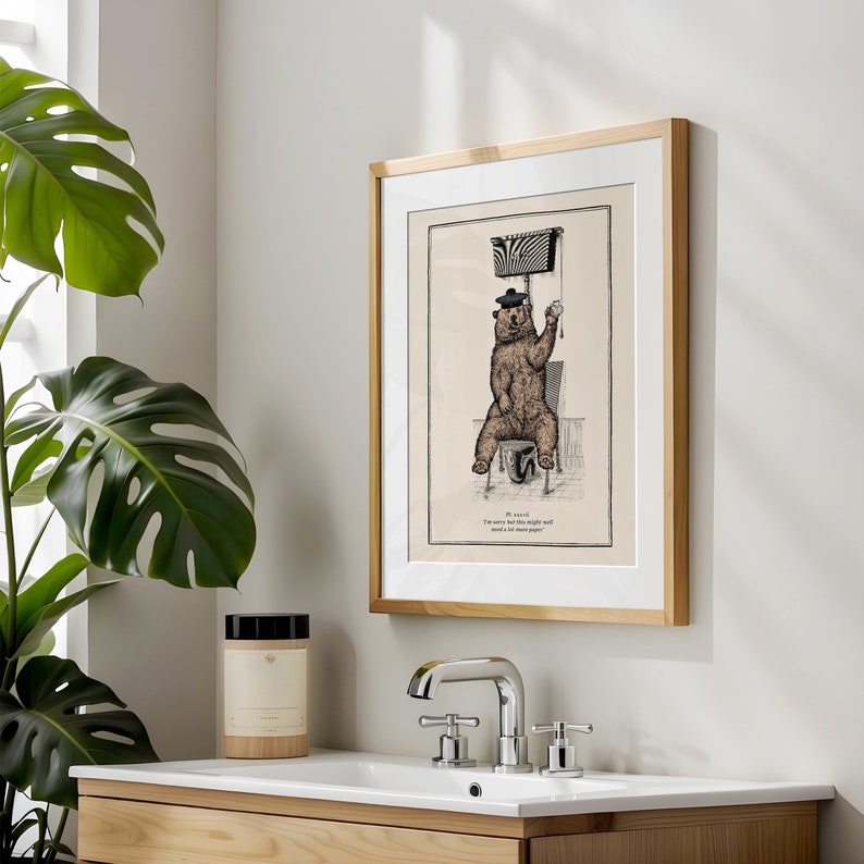 May include: A framed illustration of a bear wearing a beret and sitting on a toilet. The text below the bear reads "I'm sorry but this toilet roll stand is out of toilet paper."