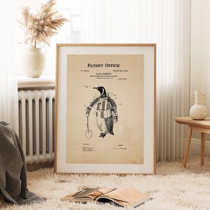 May include: A framed vintage patent print featuring a penguin in a protective suit, holding a shovel. The print, titled "Robotic Army for Polar Explorers," is on aged paper with the text "Patent Office" at the top. The penguin illustration is in black and white.