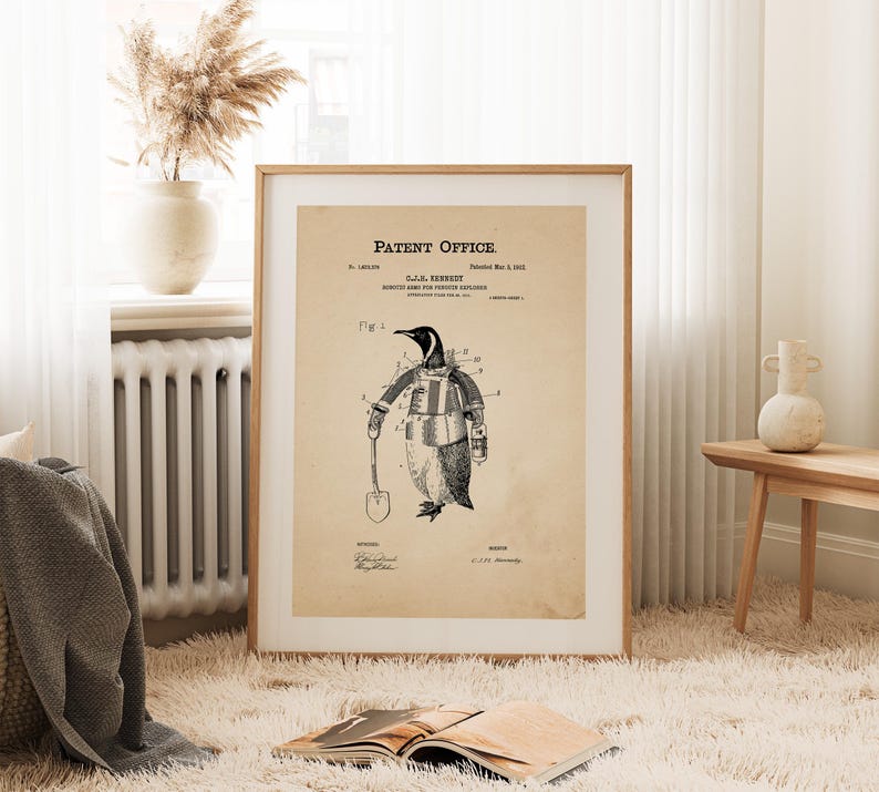 May include: A framed vintage patent print featuring a penguin in a protective suit, holding a shovel. The print, titled "Robotic Army for Polar Explorers," is on aged paper with the text "Patent Office" at the top. The penguin illustration is in black and white.