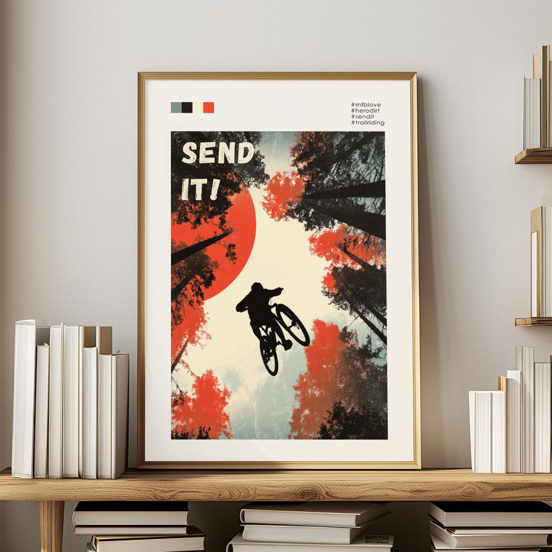 May include: A framed poster with a gold border features a mountain biker silhouetted against a red sun and tall trees. The words "SEND IT!" are in bold letters. The color palette includes red, black, and cream.