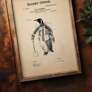 May include: Framed patent illustration of a penguin wearing robotic arms and holding a shovel. The patent is titled "Robotic Arms for Penguin Explorer" by C.J.H. Kennedy, patented March 5, 1912. The artwork is in a wooden frame.