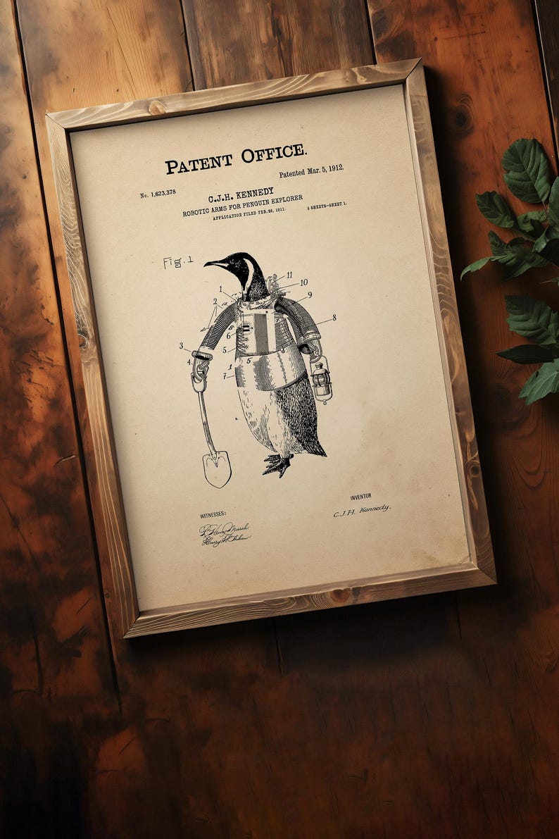 May include: Framed patent illustration of a penguin wearing robotic arms and holding a shovel. The patent is titled "Robotic Arms for Penguin Explorer" by C.J.H. Kennedy, patented March 5, 1912. The artwork is in a wooden frame.