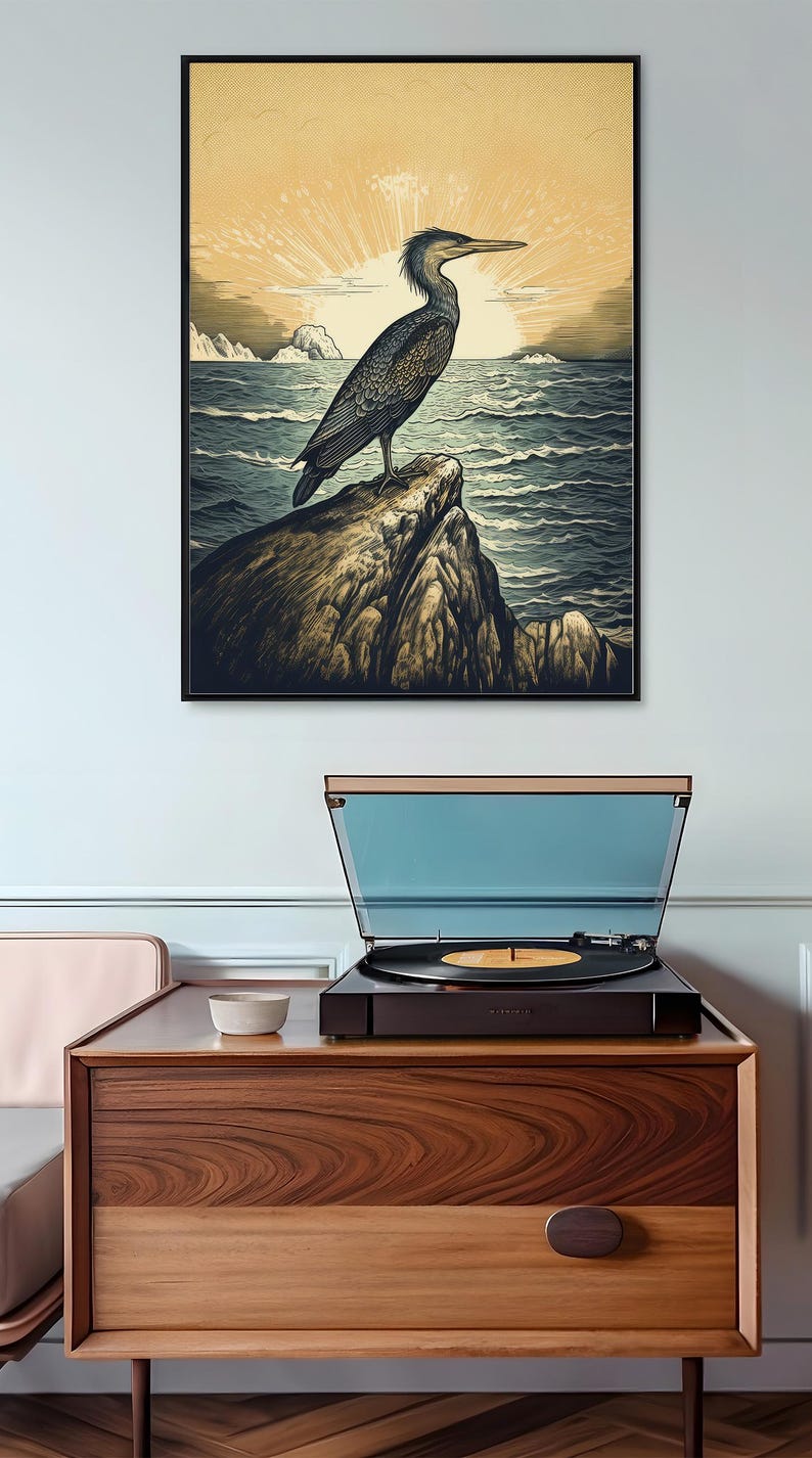 May include: A vintage-style illustration of a bird perched on a rock overlooking a body of water. The bird is dark blue and gray with a long beak. The background is a sunset with a sunburst effect.