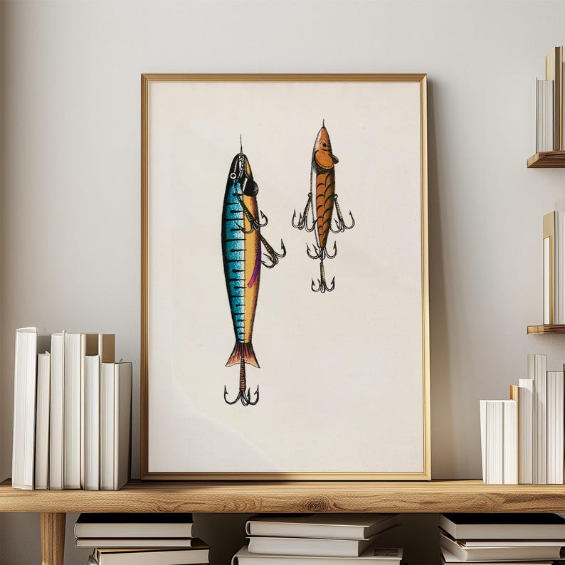 May include: A framed print featuring two vintage fishing lures. The lures are detailed with blue, orange, and brown colors, and each has multiple treble hooks. The artwork is displayed in a gold frame, suggesting a decorative piece for a fishing enthusiast.
