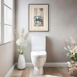 Puede incluir: Una ilustraci&oacute;n vintage de un pulpo en un inodoro. La ilustraci&oacute;n est&aacute; enmarcada y colgada en una pared de un ba&ntilde;o. El ba&ntilde;o tambi&eacute;n tiene un inodoro blanco y un jarr&oacute;n con flores blancas.