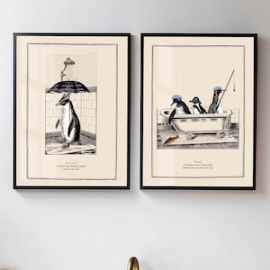 Op de afbeelding: Twee ingelijste kunstprints met pingu&iuml;ns. E&eacute;n toont een pingu&iuml;n onder de douche met een paraplu, de andere pingu&iuml;ns in een badkuip aan het vissen. Elke print heeft een zwarte lijst en een cr&egrave;mekleurige achtergrond.
